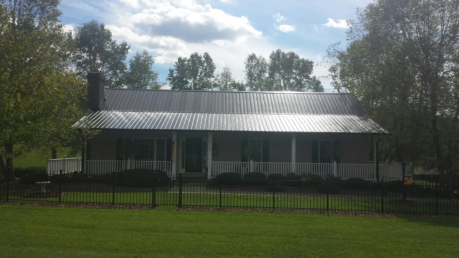 Gray metal roof on a brick ranch with a full width front porch — Gutter Guard Installation work by our crew in Verona